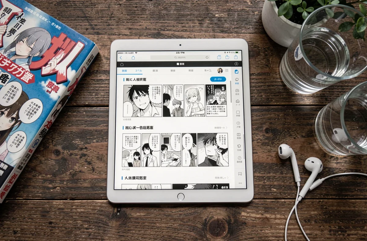 Tablette affichant un site de scan manga gratuit posée à côté d'un volume physique, symbolisant le débat sur la légalité de la lecture gratuite en ligne